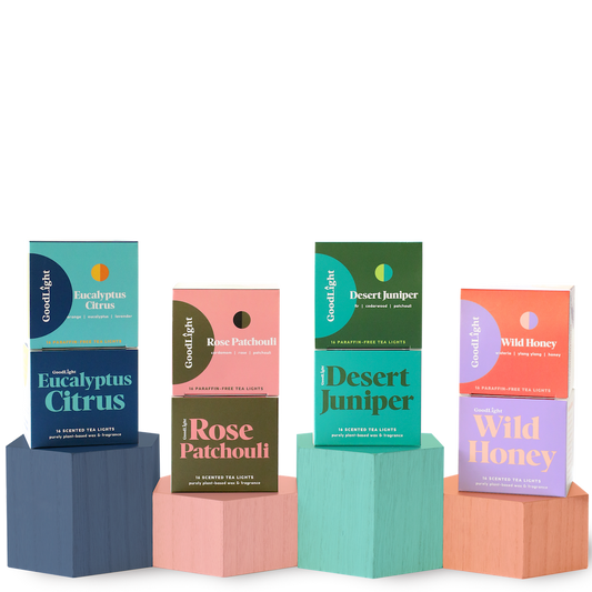 Four boxes of GoodLight candles on colorful geometric blocks against a white background