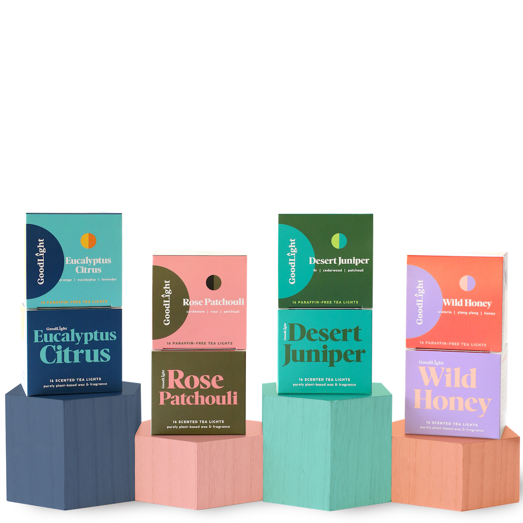 Four boxes of GoodLight candles on colorful geometric blocks against a white background.