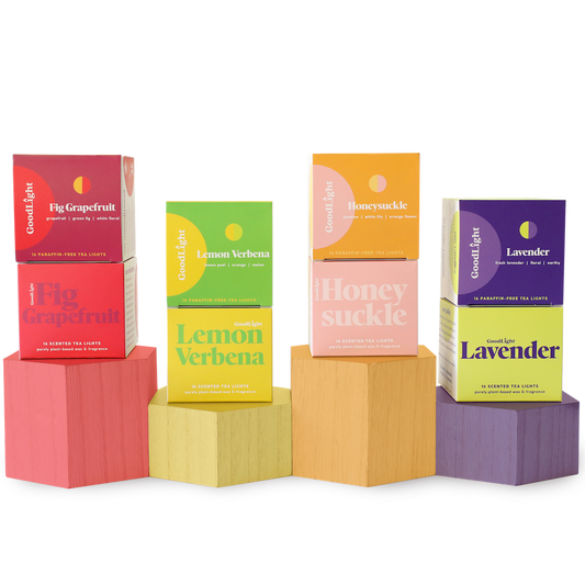 Four boxes of GoodLight candles on colorful geometric blocks against a white background