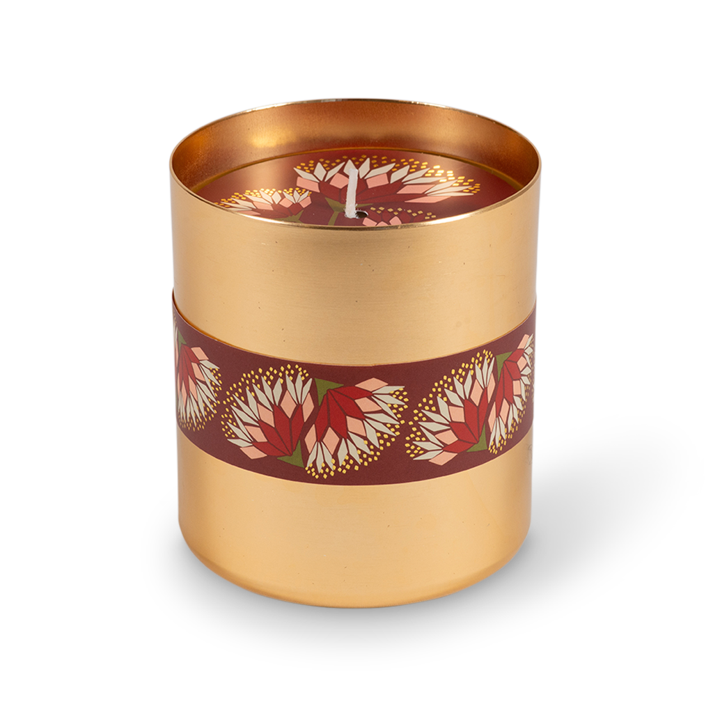 A cylindrical gold metal candle tin with a dark red band decorated with red and white floral motifs, shown on a clean white background.