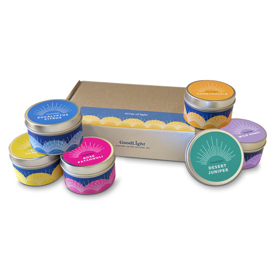 Collection of small candles in colorful tins with a GoodLight cardboard box on a white background.