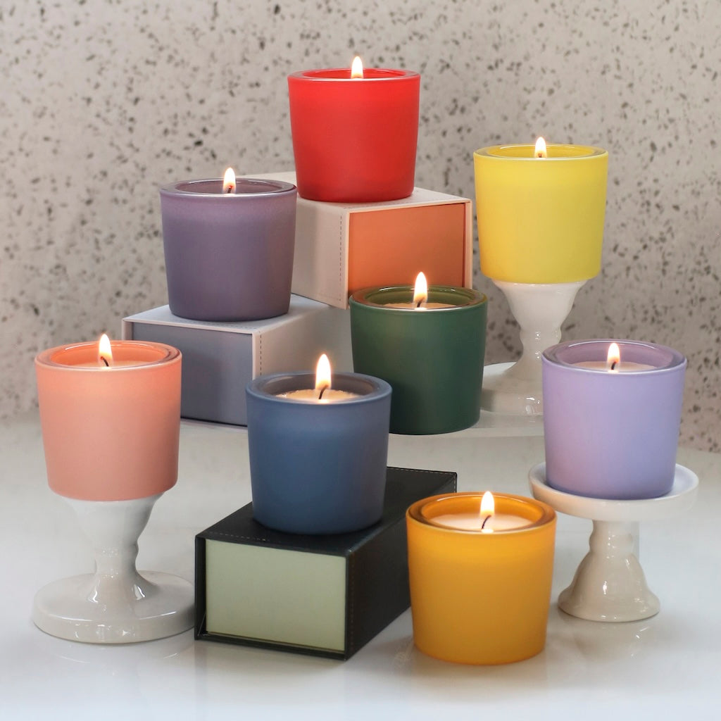 Colorful GoodLight matte votives in various holders on a table