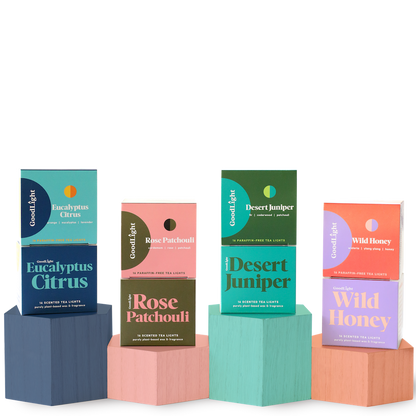 Four boxes of GoodLight candles on colorful geometric blocks against a white background