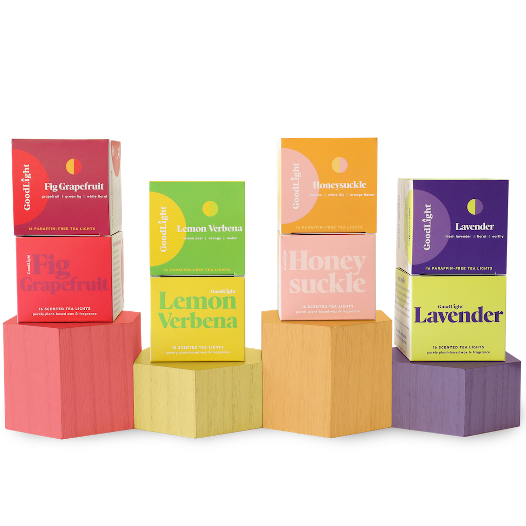 Four boxes of GoodLight candles on colorful geometric blocks against a white background