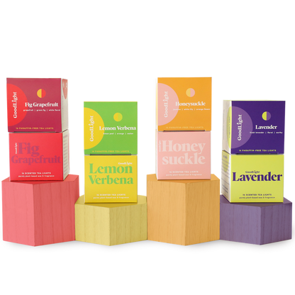 Four boxes of GoodLight candles on colorful geometric blocks against a white background