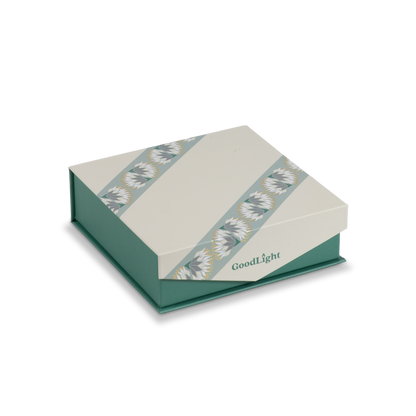 A GoodLight branded square gift box with a cream-colored lid featuring two diagonal patterned bands and a teal-green base, shown on a plain white background.