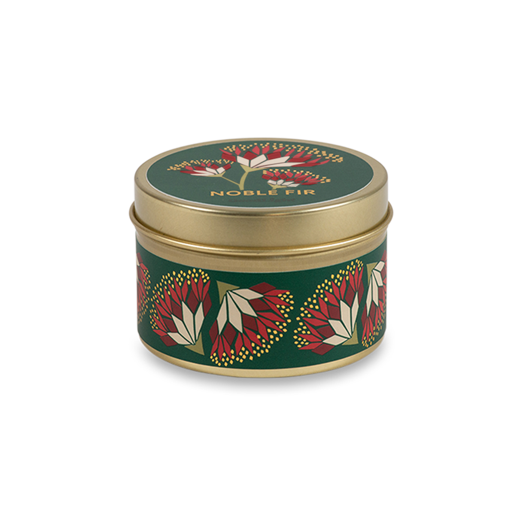 A round metal gold tin candle with a gold lid and base, featuring a green label decorated with red and pink flowers. The text on the lid reads "Noble Fir"  with GoodLight branding. 