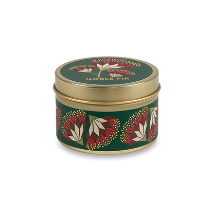 A round metal gold tin candle with a gold lid and base, featuring a green label decorated with red and pink flowers. The text on the lid reads "Noble Fir"  with GoodLight branding. 