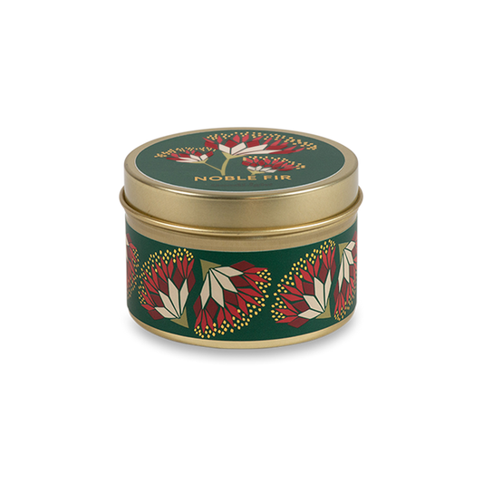 A round metal gold tin candle with a gold lid and base, featuring a green label decorated with red and pink flowers. The text on the lid reads "Noble Fir"  with GoodLight branding. 