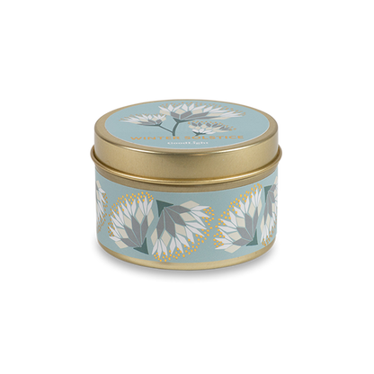 A round metal gold tin candle with a gold lid and base, featuring a light blue label decorated with cream and white flowers. The text on the lid reads "Winter Solstice"  with GoodLight branding. 