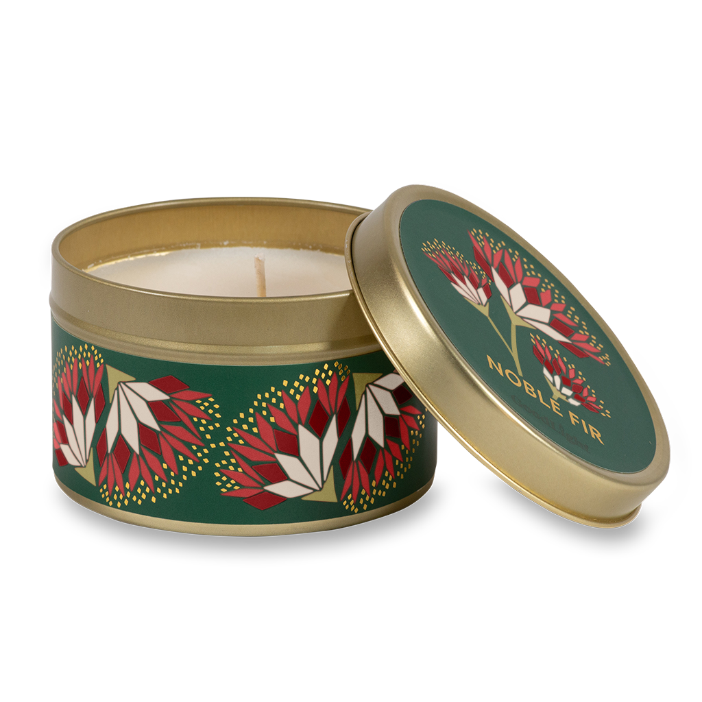 A round metal gold tin candle with a gold lid and base, featuring a green label decorated with red and pink flowers. The text on the lid reads "Noble Fir"  with GoodLight branding. 