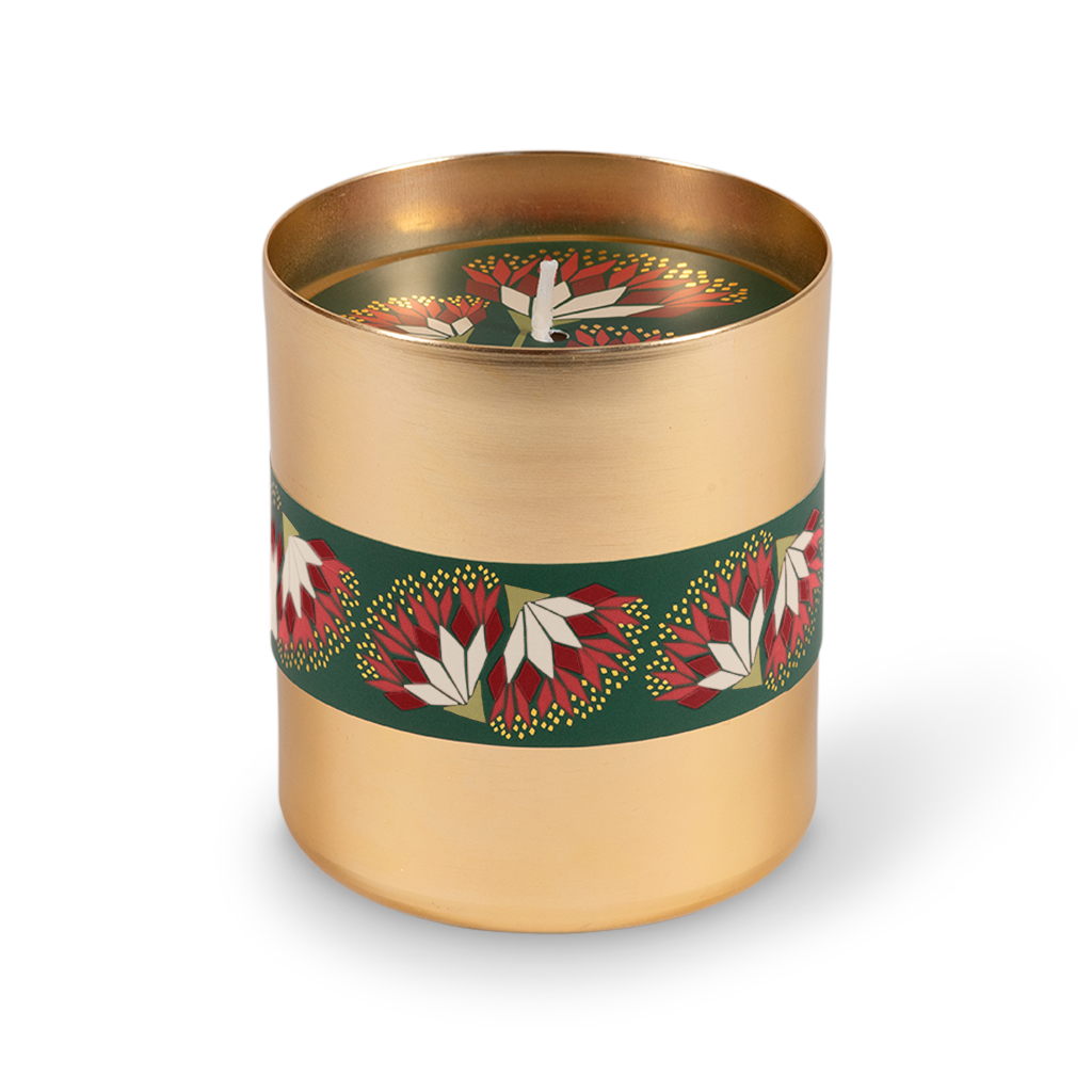 A cylindrical gold metal candle tin with a dark green band decorated with red and white floral motifs, shown on a clean white background.