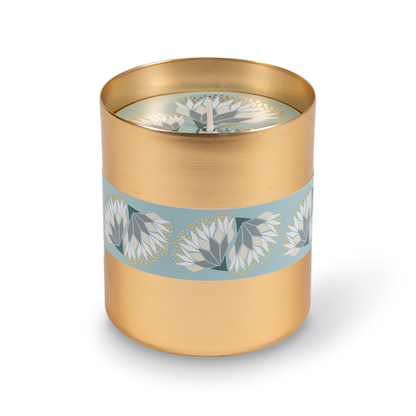 A cylindrical gold metal tumbler featuring a decorative light blue band wrapped around the middle with white and gray floral motifs.